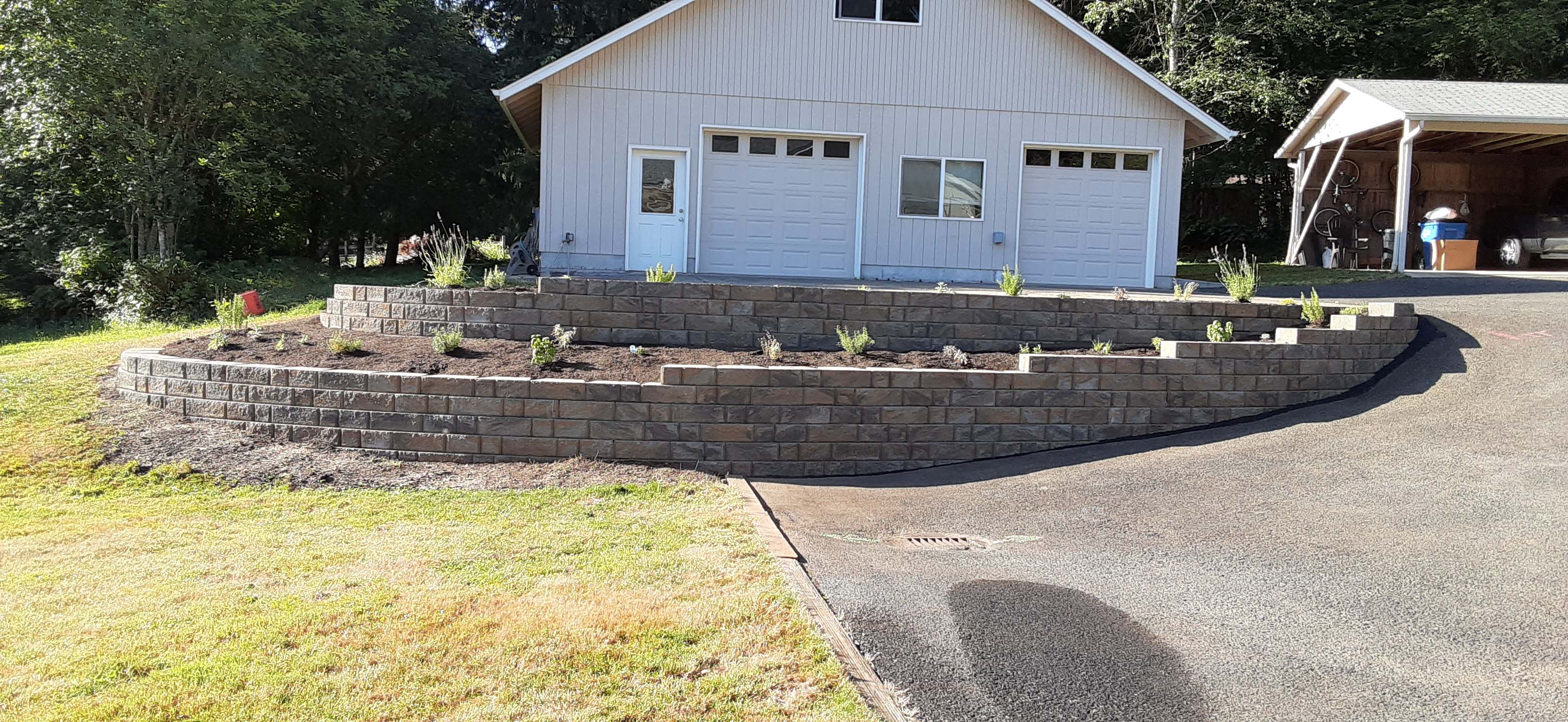 Fully rebuilt, two tiered retaining wall in front of a garage and driveway