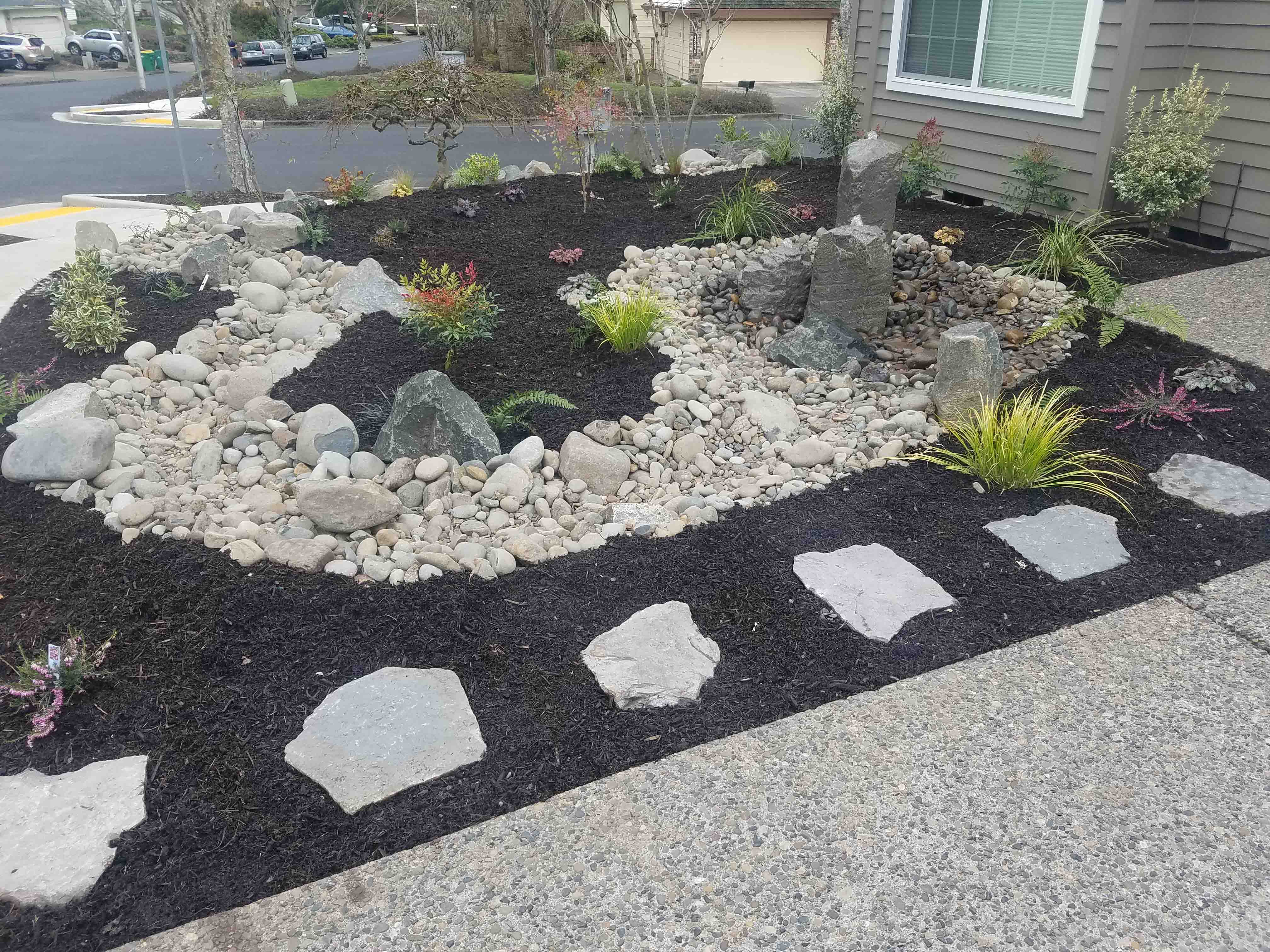 All new front yard filled with mulch and stone including a new stone water fountain and new plants